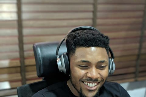 A smiling young man wearing headphones at his desk